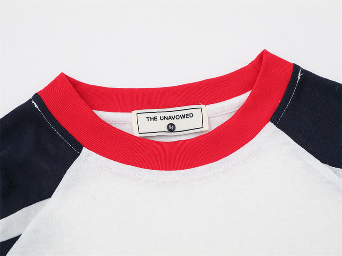 Close-up of the white tee's red crew neckline, navy raglan panels, stitching, and sewn neck label