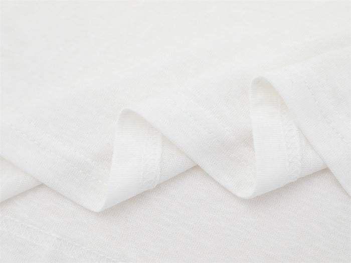 Close-up of the white shirt fabric folded into soft ridges, showing its fine knit texture