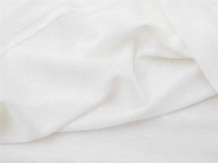 Close-up of the white shirt fabric draped in loose folds, highlighting its smooth knit texture