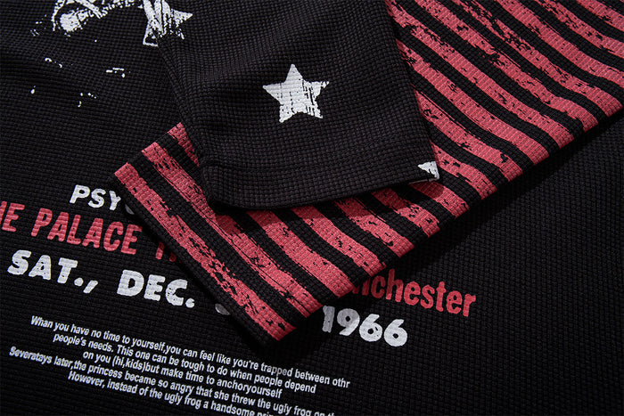 Close-up of black tee sleeve and cuff showing red horizontal stripes, a white star, and partial front lettering