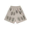 Baggy mens washed sweat shorts in faded beige with spray-shadow print and vertical 'a happy day' graphic on the leg