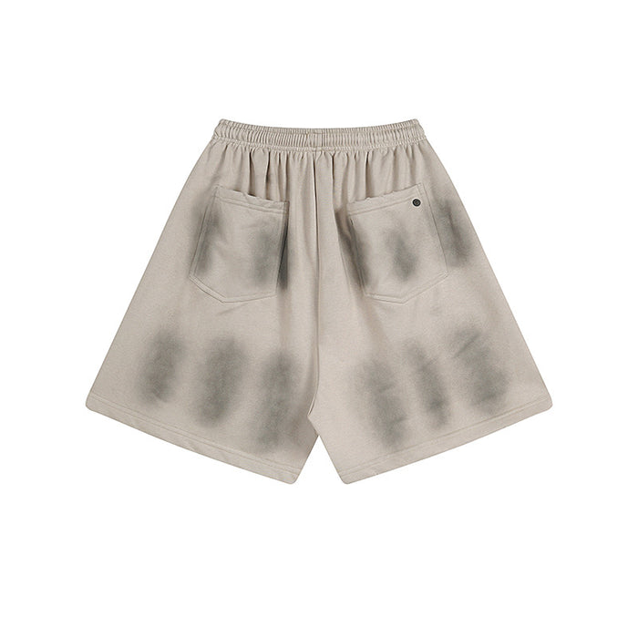 Back view of washed beige shorts showing two stitched patch pockets and elastic waistband