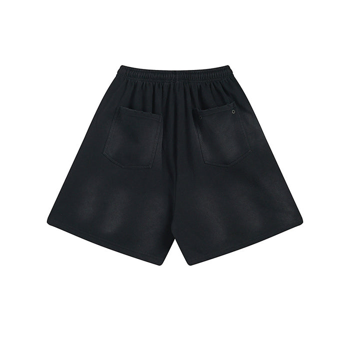 Back view of black shorts showing two stitched patch pockets and elastic waistband