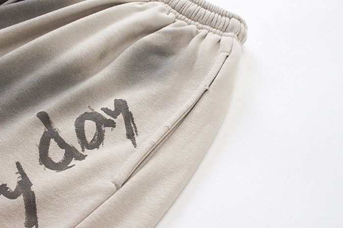 Close-up of washed beige shorts showing textured fabric, side seam, and partial dark graphic lettering