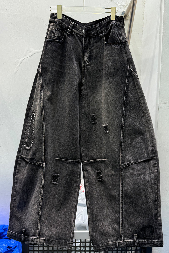 Front view of black washed wide-leg jeans with distressed rips, utility pockets, and panel stitching