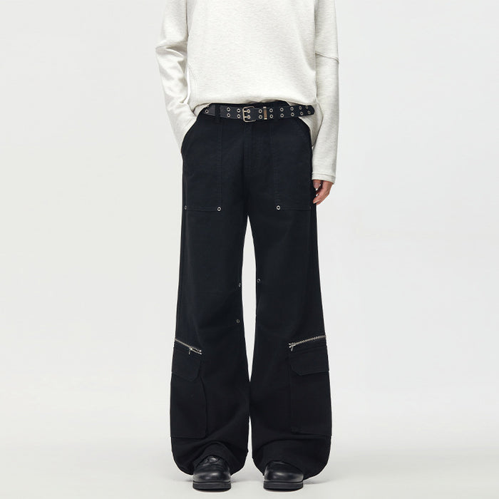 Black wide-leg cargo pants worn from the front, featuring multiple pockets, silver zippers, and snap details