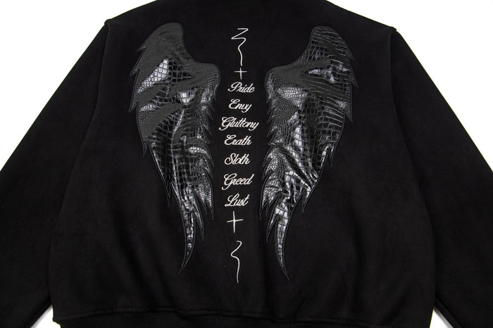 Close-up of black hoodie back graphic with reflective textured angel wings and vertical seven deadly sins lettering
