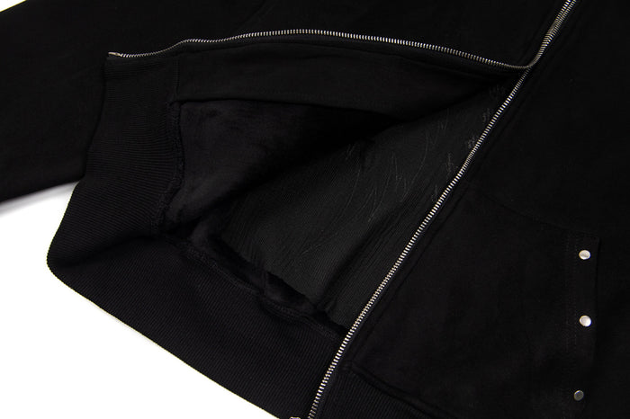 Close-up of the black hoodie interior showing soft lining, open zipper, ribbed hem, and pocket edge