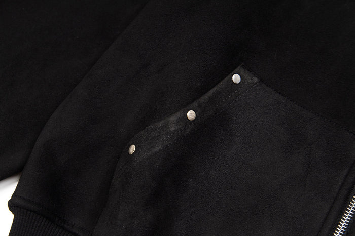 Detailed view of a black hoodie pocket showing its curved flap, stitching, and three silver snaps