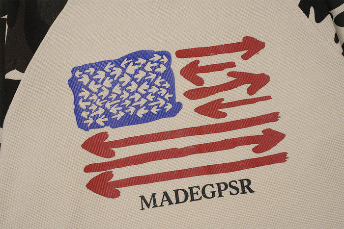Close-up of the beige shirt graphic with a blue patterned block, red arrows, and MADEGPSR text