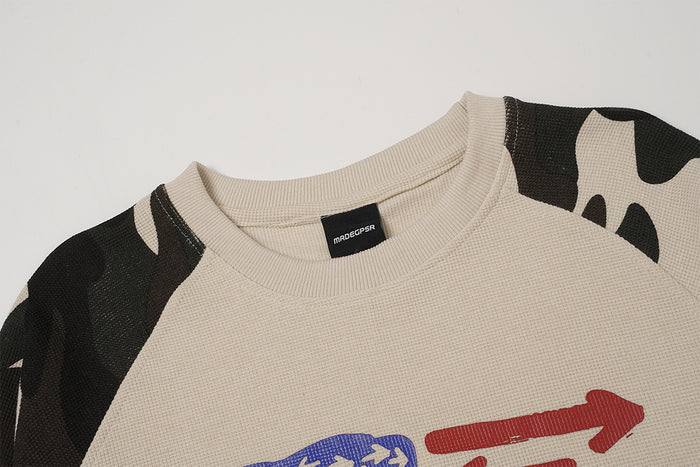 Close-up of the beige crew neckline, raglan seam, camouflage shoulder panels, and woven fabric texture
