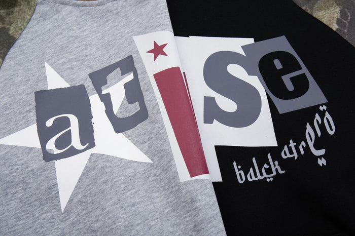 Close-up of the hoodie chest graphic with layered letters, white star shapes, and red accents