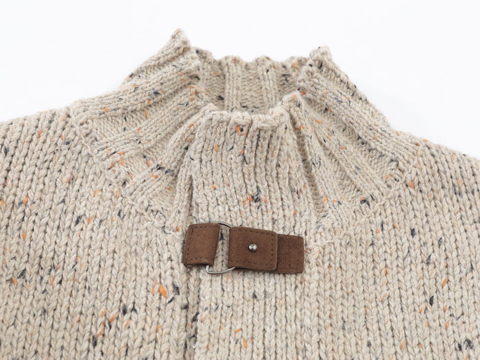 Close-up of a speckled beige knit cardigan mock neck and leather buckle closure