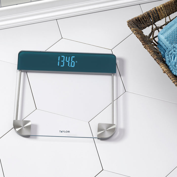 Digital glass scale with magic display reading 134.6 lb on white tiled floor