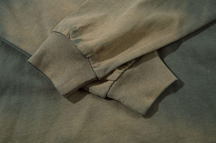 Close-up of the olive shirt sleeve and ribbed cuff showing acid-washed fading and stitched construction
