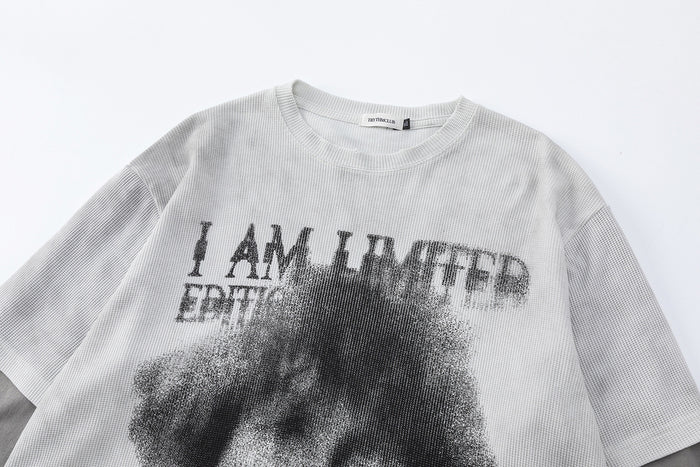 Upper front detail of the light gray waffle knit shirt showing the crew neck and distressed graphic text