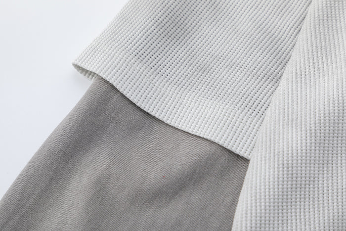 Close-up of the layered sleeve construction with a light waffle knit short sleeve over a gray long sleeve