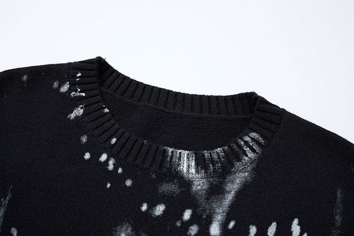 Close-up of the black sweater's ribbed crew neckline with gray paint streaks and white splatter details