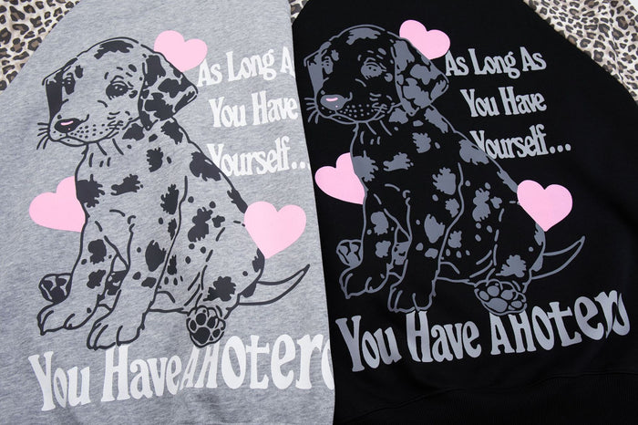 Close-up comparison of gray and black hoodie fronts showing puppy artwork, pink hearts, and white lettering