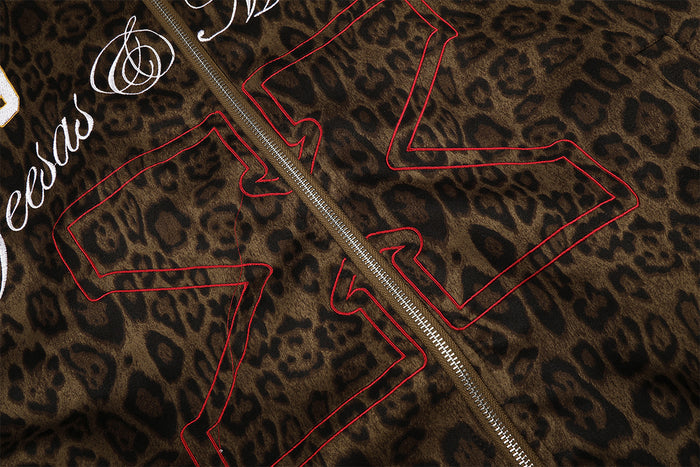 Close-up of the red outlined varsity graphic across the brown leopard-print front beside the zipper
