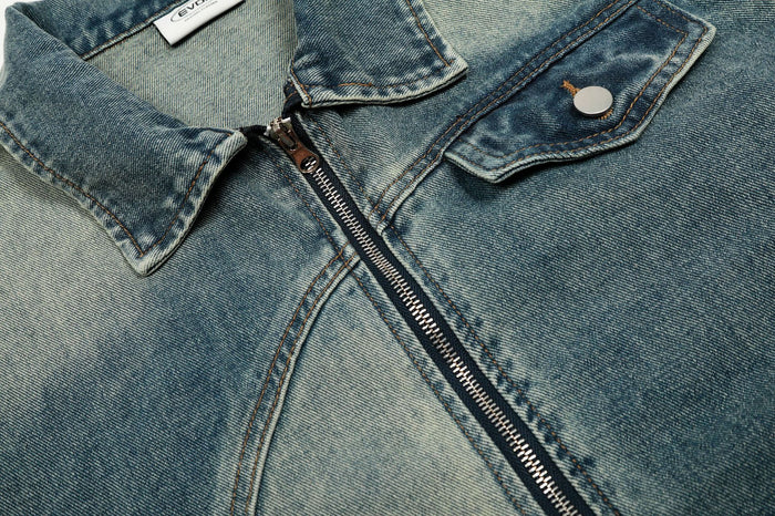 Detailed view of the denim jacket collar, metal zipper and chest flap pocket with a round button closure
