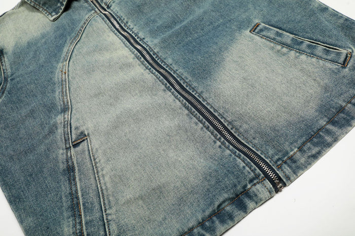Lower front detail of the light wash denim jacket showing the metal zipper, curved seam and welt pocket