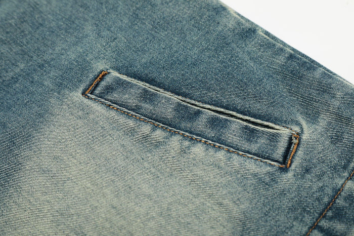 Close-up of a rectangular welt pocket stitched into the faded light wash denim jacket front