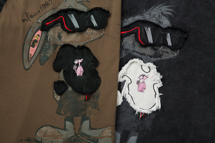 Close-up of brown and black shirt graphics featuring raised sunglasses and rabbit-shaped fabric patches