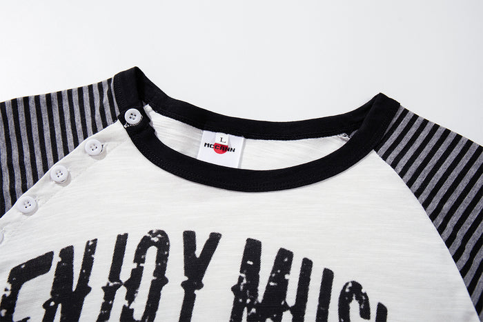 Close-up of white raglan shirt neckline with black trim, striped shoulder, button placket and printed graphic