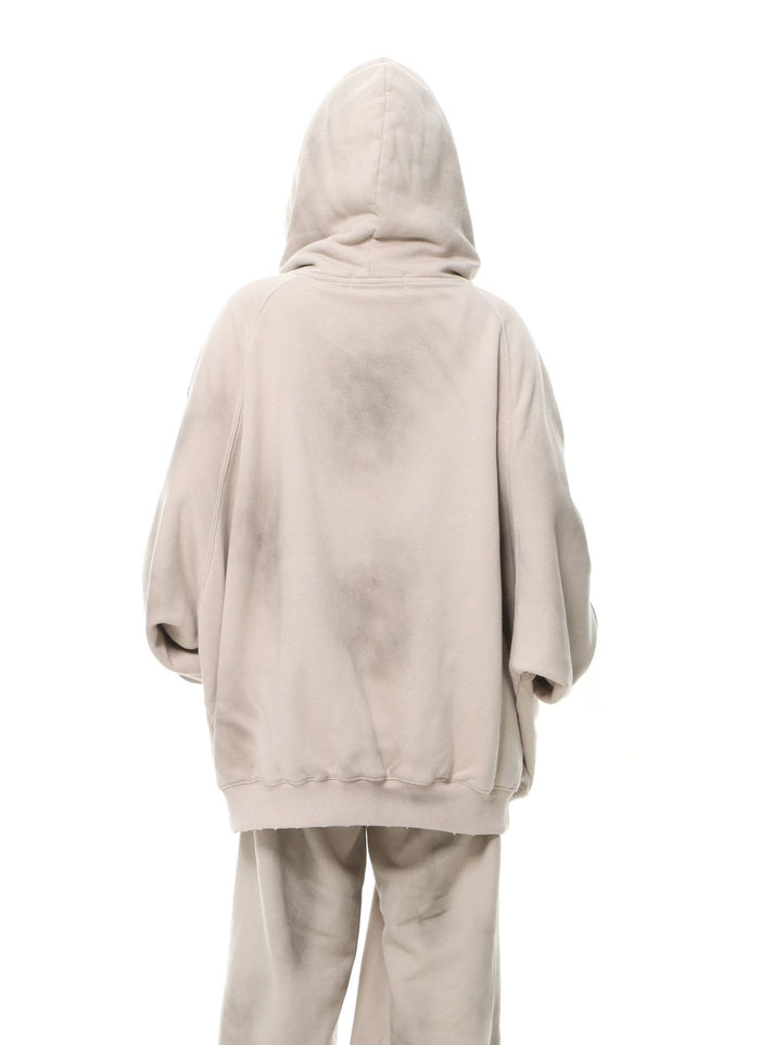 Back view of a washed beige oversized hooded sweatshirt and matching pants with faded shading