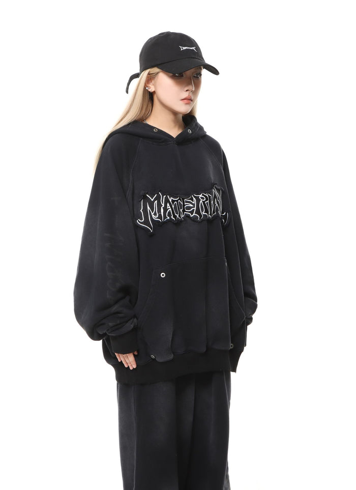 Three-quarter view of a model in a black oversized hoodie with chest lettering and matching pants