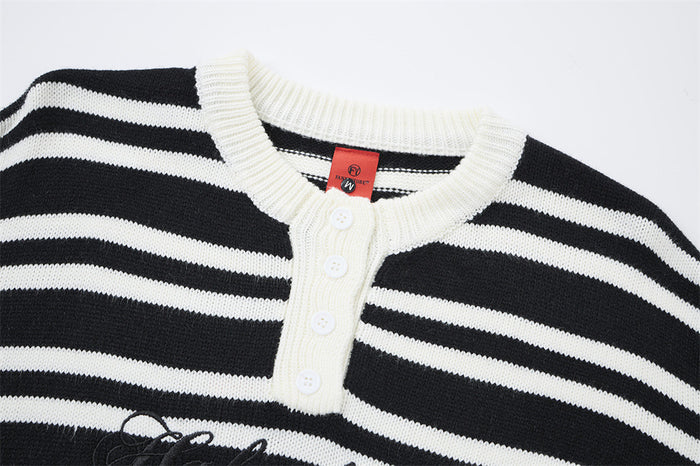Close-up of a black and white striped knit henley collar with white ribbing, four buttons, and placket