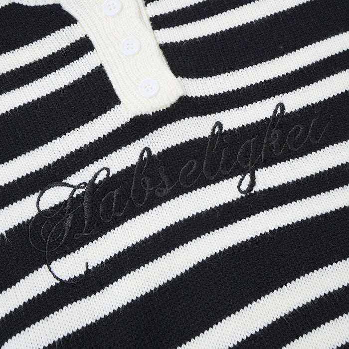 Close-up of black script embroidery across the chest of a black and white striped knit henley sweater