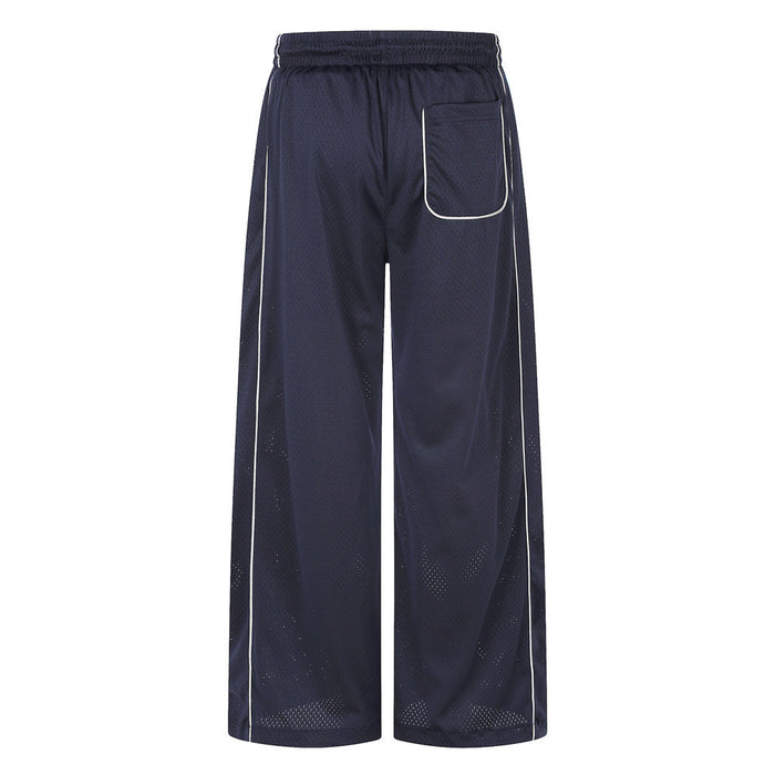 Back view of navy wide-leg mesh pants with an outlined pocket, white piping and perforated mesh texture
