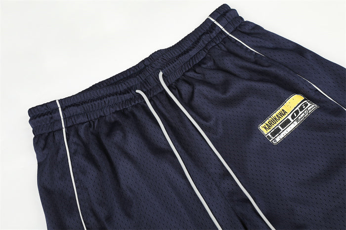 Close-up of navy mesh pants showing the elastic drawstring waistband, white piping and rectangular logo patch