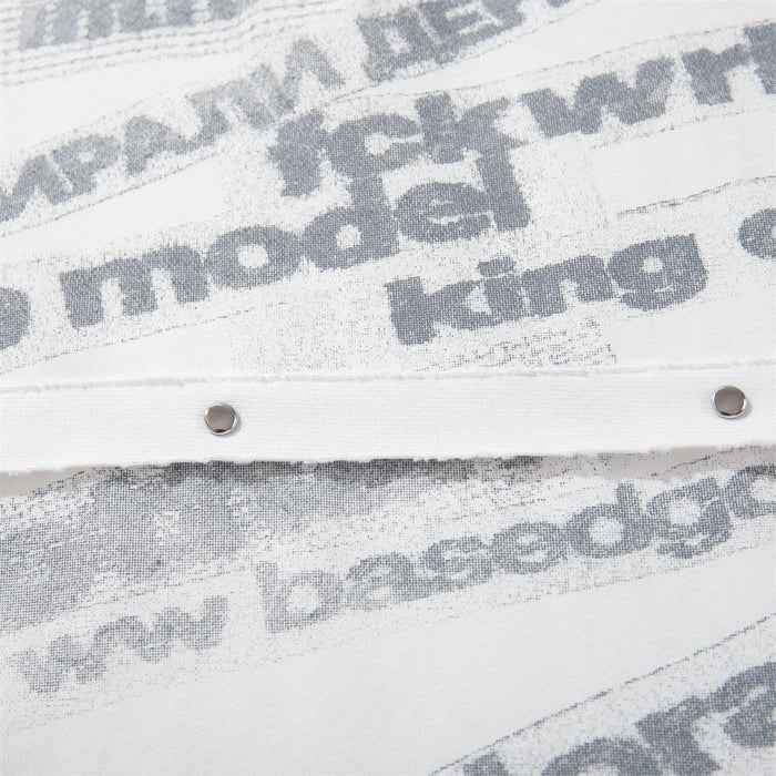 Detailed view of gray letter print, layered fabric panels, and metal studs on the shirt front