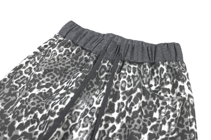 Close-up of the grey elastic waistband, drawstring, and side pocket on leopard-print sweatpants
