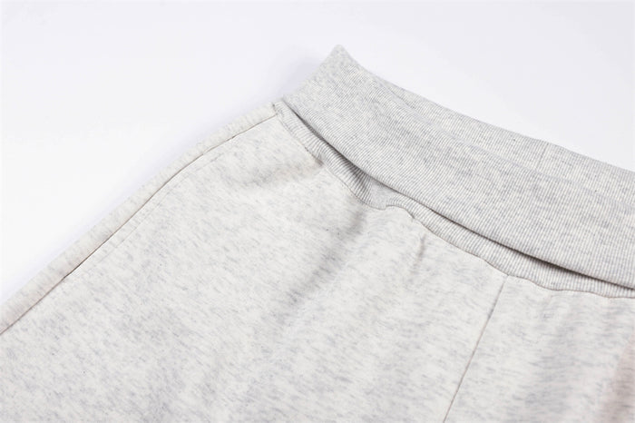 Close-up of the light gray sweatpants ribbed waistband and stitched front pocket seam