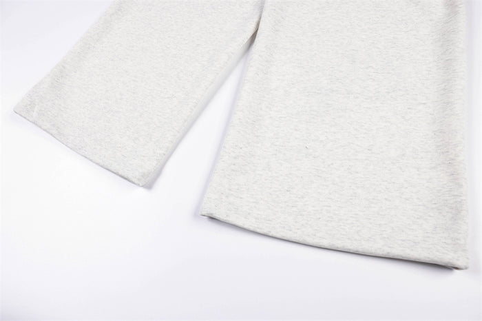 Close-up of the wide straight-leg openings on light gray sweatpants