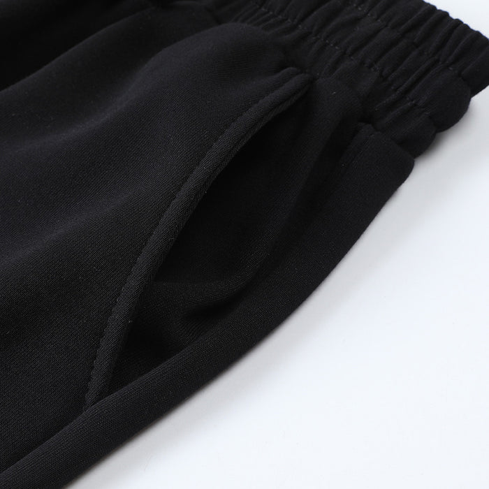Close-up of black sweatpants with an elastic waistband, drawstring, and angled side pocket