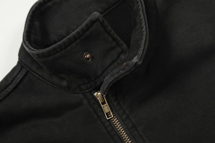 Open stand collar detail on the black jacket with a gold snap and partially visible front zipper