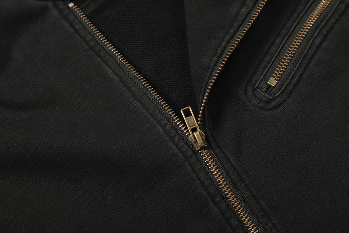 Close-up of the black jacket front showing the main gold zipper and a zippered chest pocket