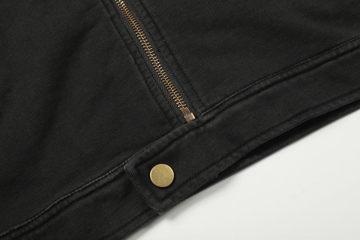 Lower jacket detail showing a gold zipper end and gold snap fastener on the black hem
