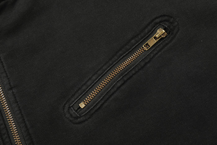 Close-up of a horizontal gold zippered pocket set into the black jacket front