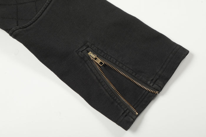 Black jacket sleeve cuff with a gold side zipper and stitched cuff seam