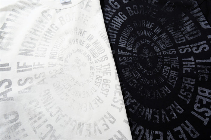 Close-up comparison of the white and black shirts showing their contrasting spiral text graphics