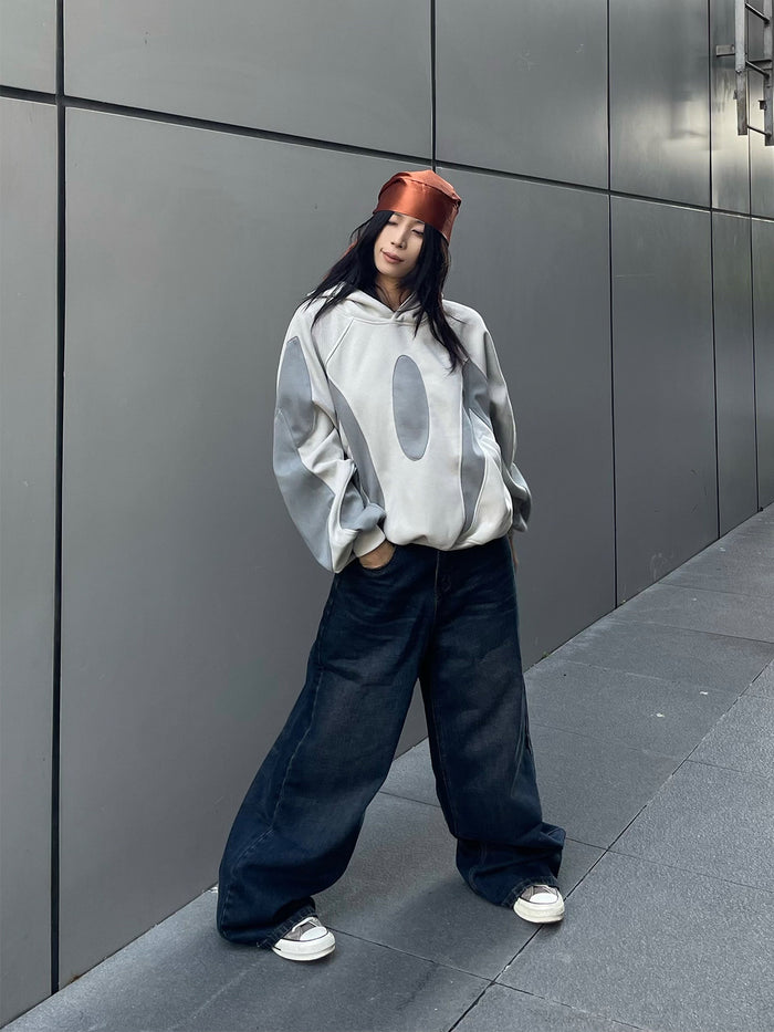 Full-body model view of a two-tone gray oversized patchwork hoodie with hood and front pocket