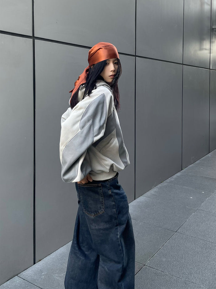 Side view of an oversized two-tone gray hoodie showing its layered sleeve and side patchwork