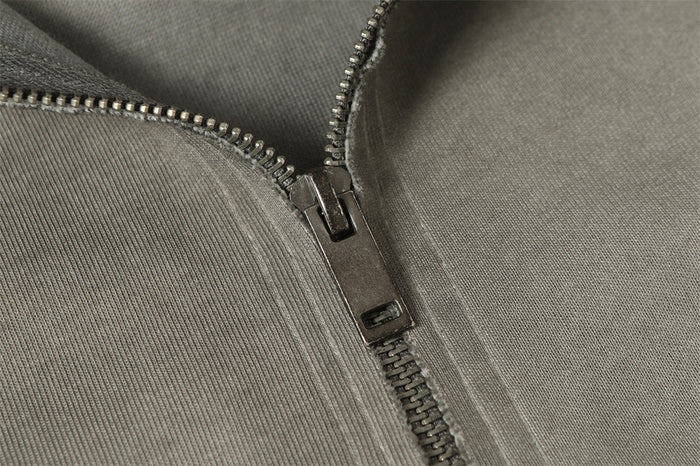 Close-up detail of the metal front zipper and zipper slider on washed gray hoodie fabric