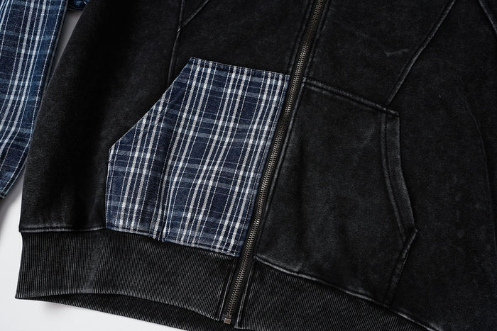 Close-up of the black hoodie front showing a blue plaid pocket, kangaroo pocket, zipper and ribbed hem